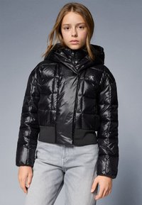 Fekete, rövidített puffert jacket fényes bevonattal, kapucnival és elasztikus derékkal. Zipzárral záródik és steppelt mintázattal rendelkezik.