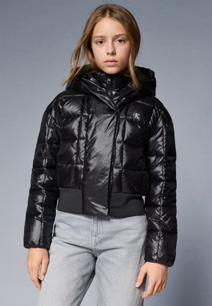 Fekete, rövidített puffert jacket fényes bevonattal, kapucnival és elasztikus derékkal. Zipzárral záródik és steppelt mintázattal rendelkezik.