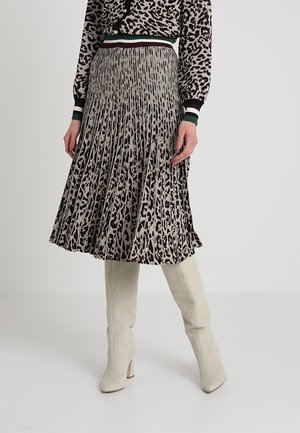 Plisowana spódnica midi w nadruk panterkowy, zestawiona z dopasowanym topem z długim rękawem oraz białymi, wysokimi kozakami na obcasie do kolan.