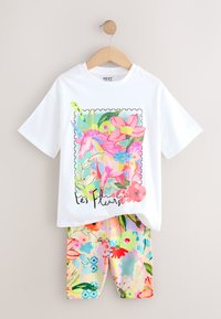Witte katoenen T-shirt met een kleurrijke eenhoornafbeelding omringd door bloemen. Gecombineerd met legging met bloemenprint in pasteltinten.