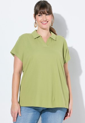 Polo shirt verde chiaro a maniche corte con colletto a V, realizzato in un tessuto teksturizzato, abbinato a jeans blu.
