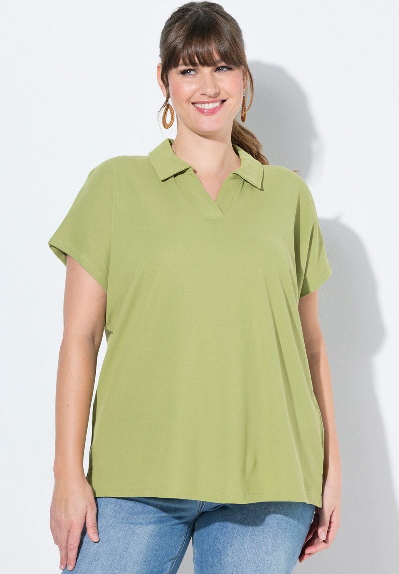 Polo shirt verde chiaro a maniche corte con colletto a V, realizzato in un tessuto teksturizzato, abbinato a jeans blu.