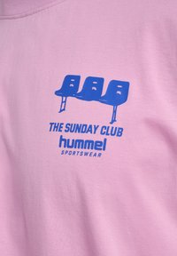 Rosa bomull t-shirt med en blå grafisk design av tre stolar och texten "THE SUNDAY CLUB" och "hummel SPORTSWEAR."