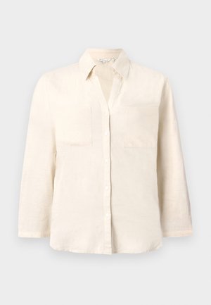 Chemise en lin beige clair avec un col, patte de boutonnage à cinq boutons et deux poches avant. Dotée de manches longues et d'une coupe décontractée.