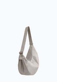 Borsa a tracolla sintetica beige con forma curva e una lunga tracolla regolabile. Presenta una texture liscia e un design minimalista.