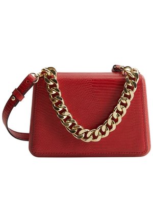 Sac à main rouge texturé avec une grande anse chaîne dorée et une bandoulière rouge réglable sur fond blanc.
