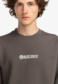 Sudadera gris oscuro hecha de tejido suave, con escote de barco y logo bordado en blanco "ELEMENT" en el pecho.