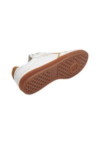 Baskets blanches avec semelle en gomme, vue de dessous, montrant un motif de bande de roulement détaillé et des accents dorés sur le côté et le talon.