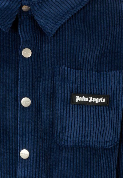 Camicia in corduroy blu navy con colletto a punta, bottoni a pressione argentati, taschino sul lato sinistro del petto e un'etichetta nera con la scritta "Palm Angels."