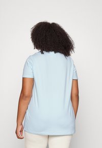 Ljusblå kortärmad t-shirt med avslappnad passform, slät textur och minimala söm detaljer, sedd från baksidan.