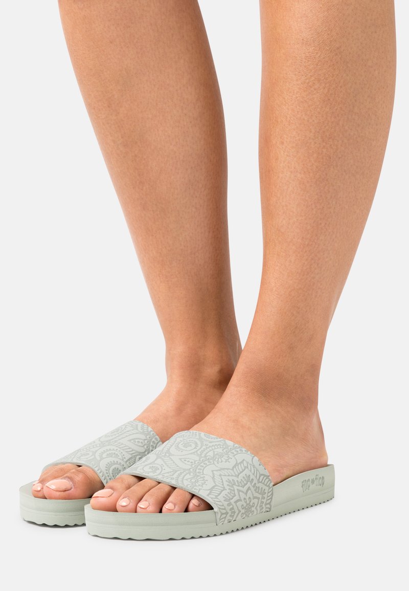 Light green slide sandals with a textured floral pattern on the strap and a patterned rubber sole. Lightweight and open-toe design.