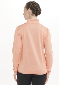 Langærmet pink træningstoppet lavet af tekstureret stof, med høj krave og tætsiddende silhuet. Har sammenskrumpede ærmer og lige kant.