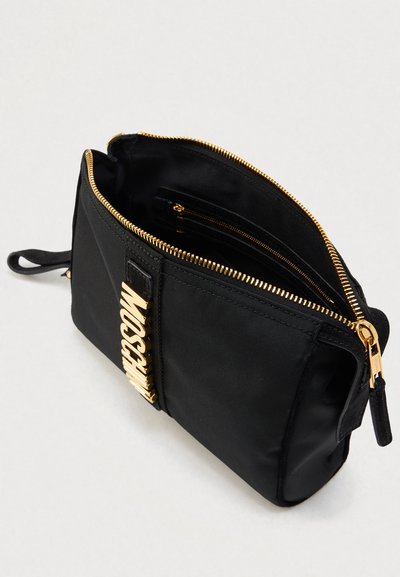 Μαύρο τσαντάκι χειρός με φερμουάρ, κατασκευασμένο από λείο υλικό, με εμφανές χρυσό λογότυπο, εσωτερικές τσέπες και λεπτή χειρολαβή για εύκολη μεταφορά.