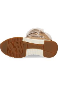 Botín de ante marrón con cuello de pelo sintético beige, que presenta una suela de goma con un patrón de relieve antideslizante y cierre de cordones. Marca Geox visible.