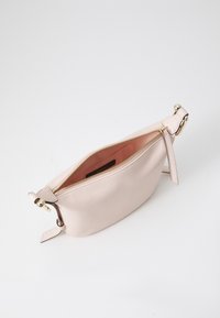 Clutch de piel rosa claro con apertura con cremallera, hardware en tono dorado y textura suave. El interior presenta un forro en tono rubor a juego.