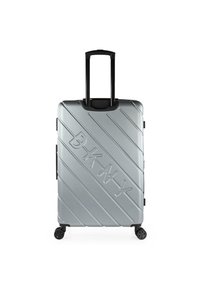 Maleta rígida plateada con líneas diagonales y el logo "DKNY" en relieve, que cuenta con un asa retráctil y cuatro ruedas negras.