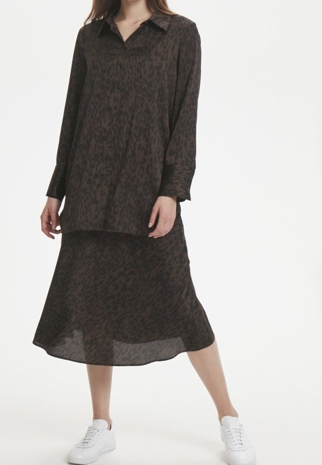 Brun leopardmönstrad långärmad skjorta med knappstängning, matchad med en koordinerad kjol. Modellen har på sig vita sneakers.