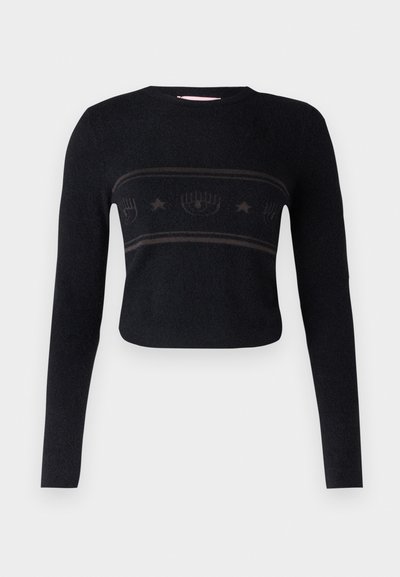 Melnā īsās piedurknes džemperis ar garām piedurknēm, kuram ir teksturēts horizontāls joslas ar stilizētiem dizainiem un zvaigznēm krūšu daļā.