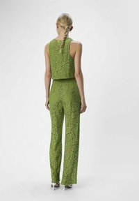 Conjunto de dos piezas verde de encaje que incluye una blusa sin mangas y pantalones a juego con pierna ancha, que exhibe un patrón floral de encaje.