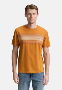 Kortærmet orange t-shirt med vandrette striber i lys lilla og beige. Fremstillet af struktureret stof med rund halsudskæring.