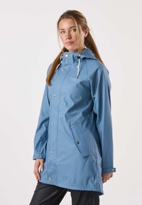 Ljust blå vattentät regnrock med huva, tryckknappar och sidoficka. Slät yta och justerbara dragsnören.