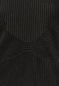 Musta kankainen pinta, jossa on tekstuurinen muotoilu ja chevron-kuvioita, sekä kiiltävä hopeinen yksityiskohta sivussa.