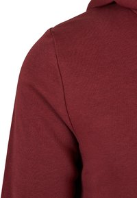 Sudadera burdeos con una textura suave, de corte estructurado y relajado. Costuras visibles en la costura del hombro, sin logotipos ni detalles adicionales.