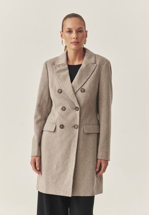 Beige dubbelzijdig jasje in een zachte textuur, met grote knopen, zijzakken en een op maat gemaakte pasvorm met een opstaande kraag.