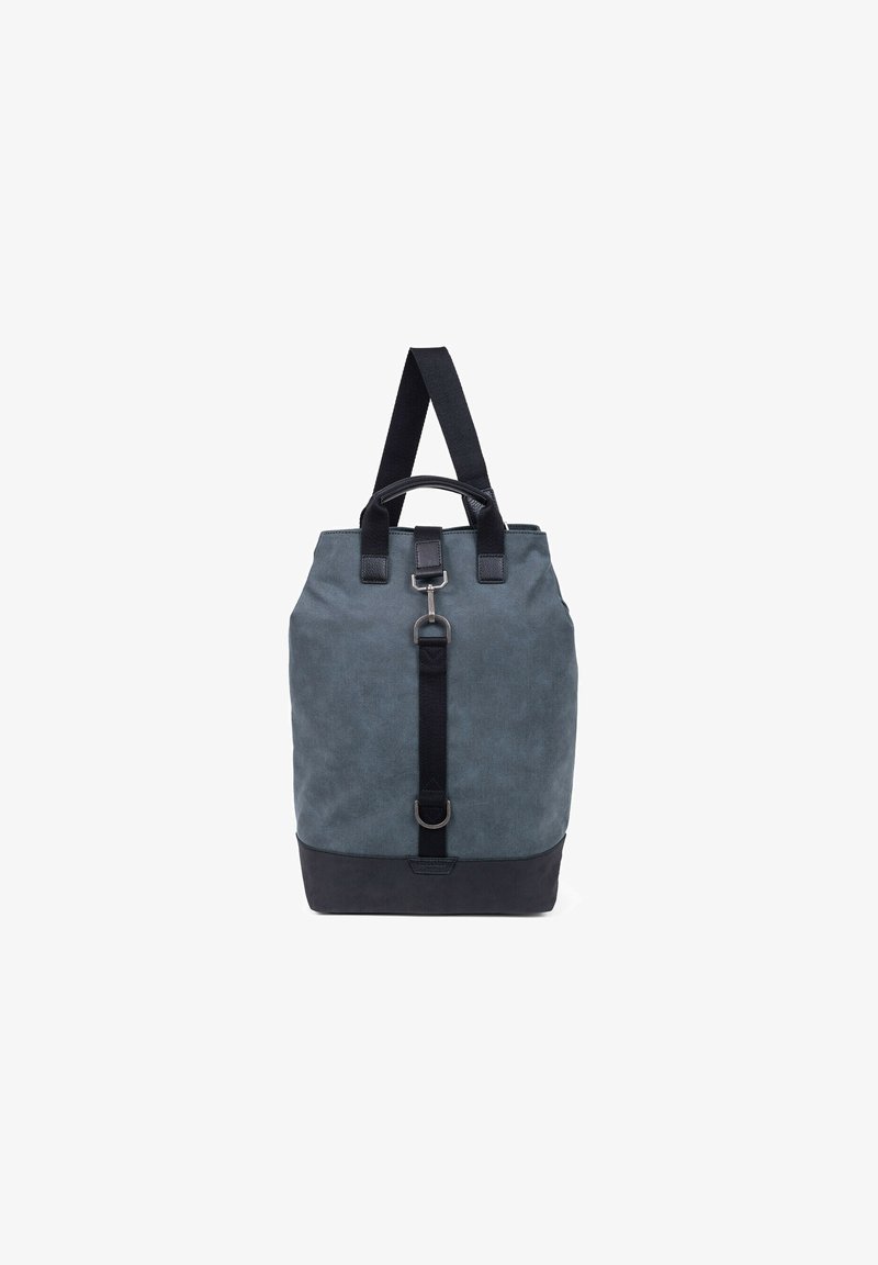 Sac à dos en toile grise avec un fond noir. Il est équipé de sangles noires, de quincaillerie en métal et d'une sangle avant avec un détail de boucle.