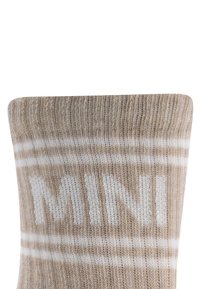 Beżowa skarpetka z białymi paskami i wyhaftowanym na grubo białym napisem "MINI". Miękka tekstura, ściągacz na górze.