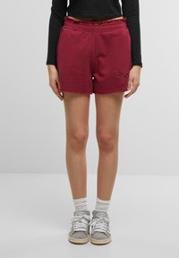 Burgunderfarget bomullsshorts med elastisk midjebånd, frynsete kant og sidelommer. Har en dekorativ brodert detalj foran.