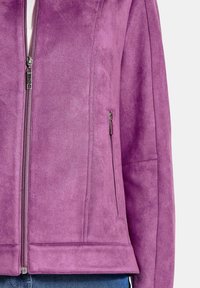Veste en nubuck violet avec une fermeture éclair devant et une poche latérale. Présente une texture lisse et un design cintré avec un ourlet à bande.