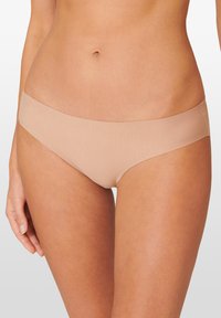 Vaaleanbeige saumatonta bikinialushousua, jossa on sileä pinta ja matala vyötärö. Mallissa on leveät sivut, eikä näkyviä alushousun saumoja.