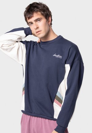Sudadera marina con paneles de acento en blanco y tonos pastel. Cuello y puños acanalados. Logo "downtown" en cursiva en el pecho. Textura suave.