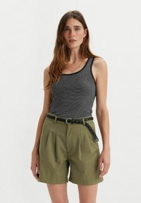 Gray ribbed tank top with black trim, paired with high-waisted olive green shorts featuring pleats and a braided black belt.