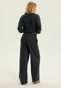 Czarnoszary skrócony sweatshirt o luźnym kroju i szerokich nogawkach, wykonany z miękkiego materiału. Posiada długie rękawy i elastyczny pas.