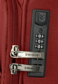 Cremallera de tela roja con tiradores de metal plateado, que presenta un panel de candado de combinación negro con pantalla numérica y botones para la entrada del código.