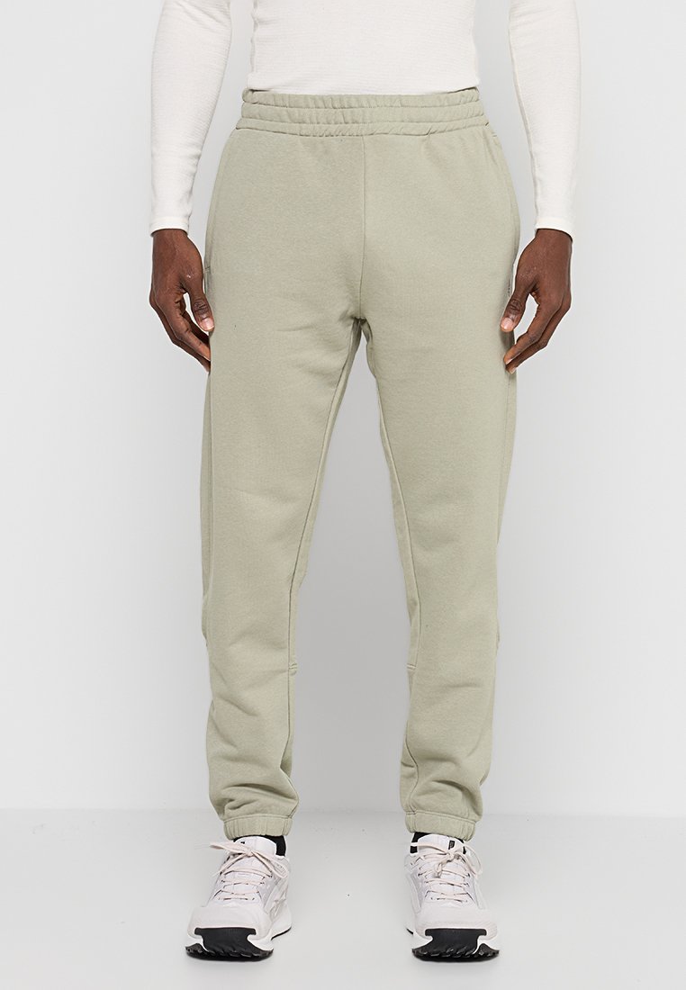 Jasnozielone spodnie dresowe o zwężanych nogawkach, z elastycznym pasem i bocznymi kieszeniami, wykonane z miękkiej bawełnianej mieszanki tkanin.