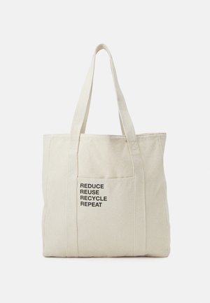 Sac cabas en toile beige avec deux anses et une poche avant avec le texte «REDUCE REUSE RECYCLE REPEAT» en lettres noires.