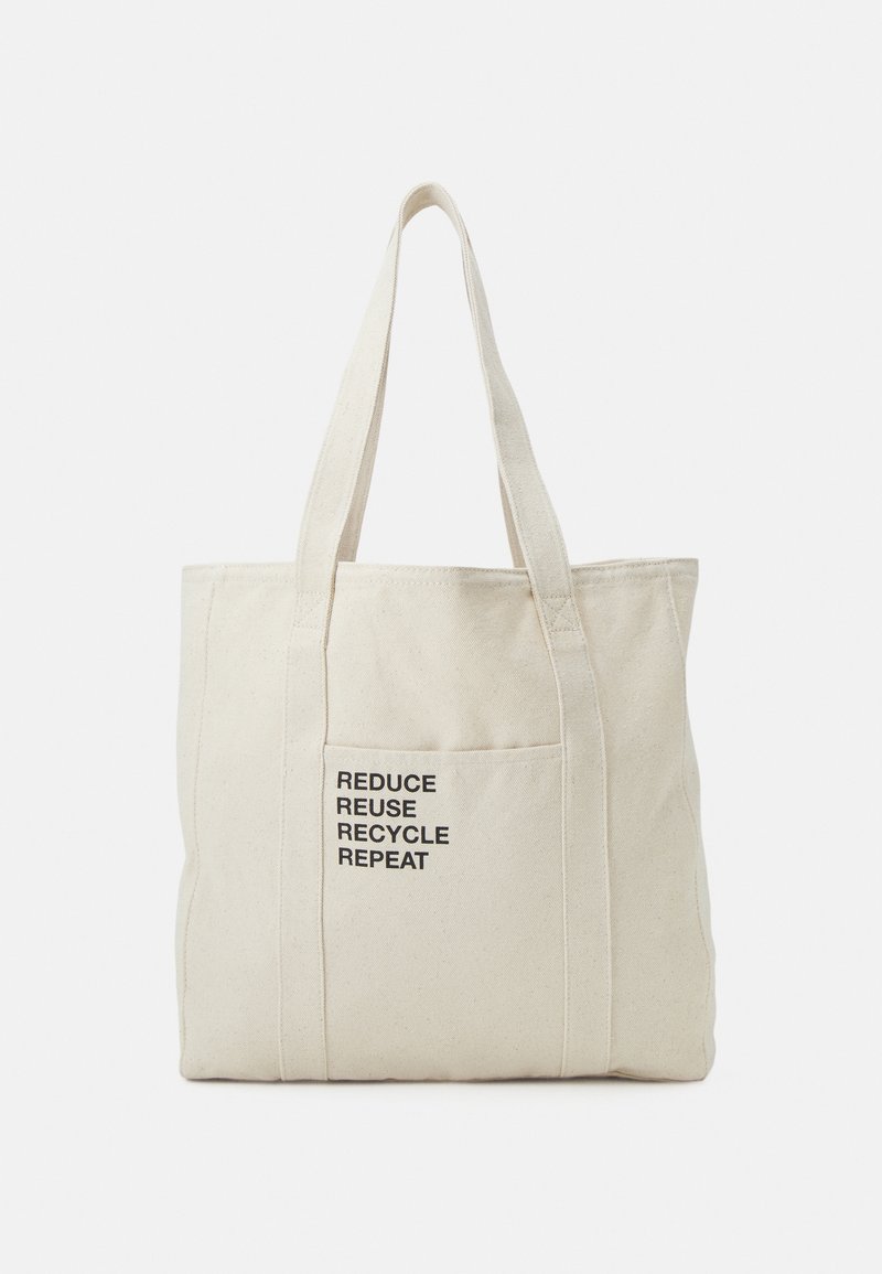 Sac cabas en toile beige avec deux anses et une poche avant avec le texte «REDUCE REUSE RECYCLE REPEAT» en lettres noires.