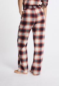 Pantalones de pijama de cuadros de algodón con un corte holgado, cinturilla elástica y un patrón de cuadros en rojo, azul marino, crema y azul, con bolsillos.