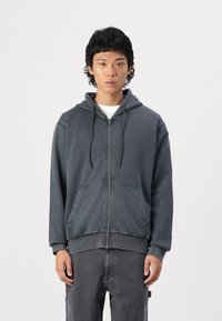 Gray zip-up hoodie with a drawstring hood, front pockets, and ribbed cuffs. The fabric has a smooth texture and a relaxed fit.