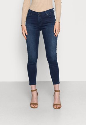 Donkerblauwe skinny jeans van denim, met een aansluitend ontwerp en enkellange snit, gecombineerd met bruine sandaaltjes met bandjes.