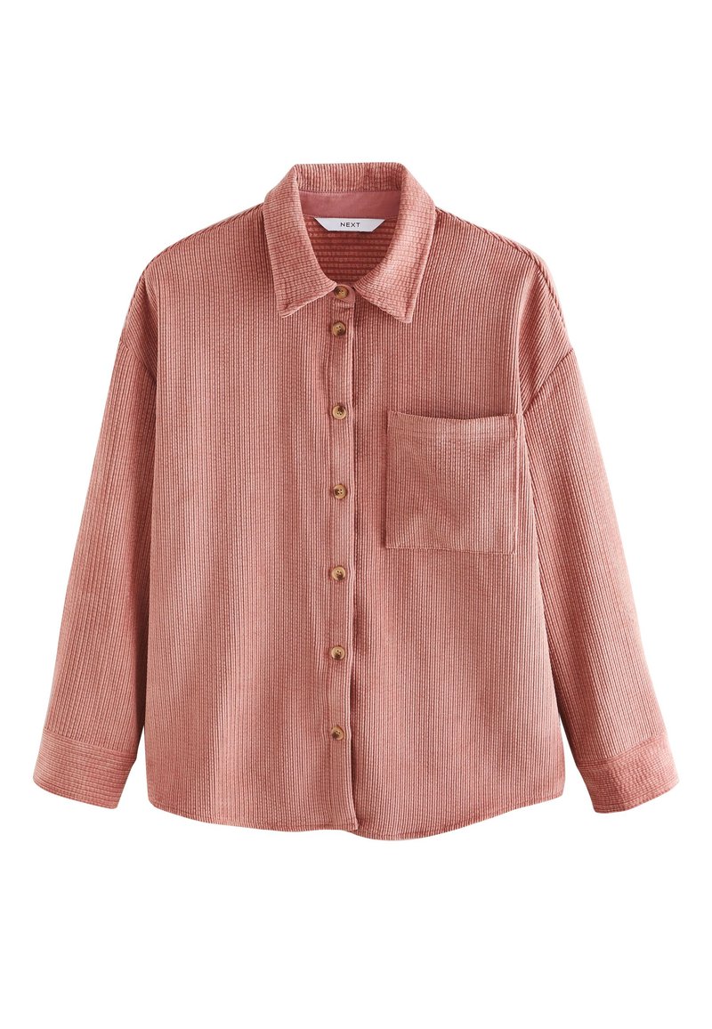 Camicia in velluto a coste color mattone con colletto, chiusura frontale con bottoni e una tasca sul petto. Presenta una trama a coste e maniche lunghe.