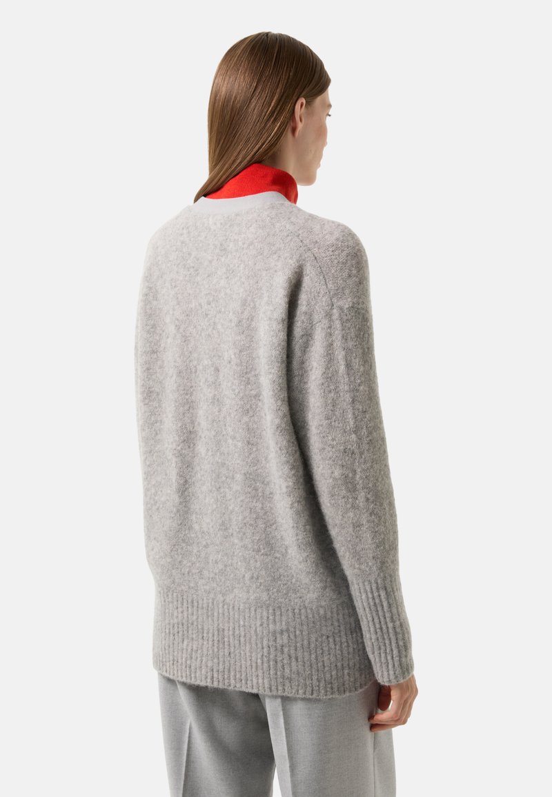 Grauer Wollpullover mit weicher Textur, geripptem Saum und langen Ärmeln, mit einem roten Kragen, der darunter hervorschaut.