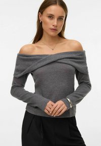 Jasnoszary sweter z opuszczonymi ramionami o strukturalnym, prążkowanym wzorze, z długimi rękawami i podwójnym kołnierzem, zestawiony z czarnymi spodniami.