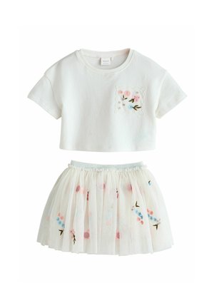 Weißes Baumwoll-Cropped-Top mit floral bestickter Tasche; mehrlagiger Tüllrock in Weiß mit bunten Blumenmustern und elastischem Bund.