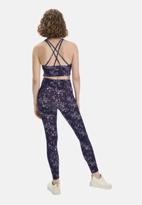 Marineblauwe bloemen sportbh met verstelbare crisscross schouderbanden, gecombineerd met bijpassende hoge taille leggings, beide van een zachte, rekbare stof.