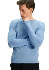 Pull en maille bleu clair avec un col rond, des manches longues et des poignets et un ourlet côtelés. Texture lisse et design ajusté.