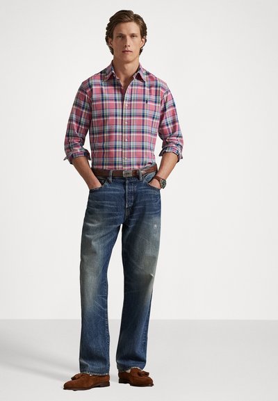 Rutete rosa og blå skjorte med lange ermer, kombinert med falmede blå jeans, brune semskede loafers og et sølvur.